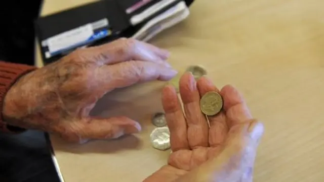 Elderly hands holding a pound coin