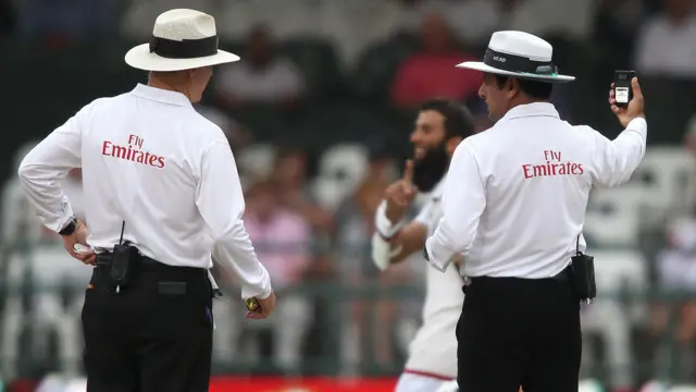 The match umpires check for bad light