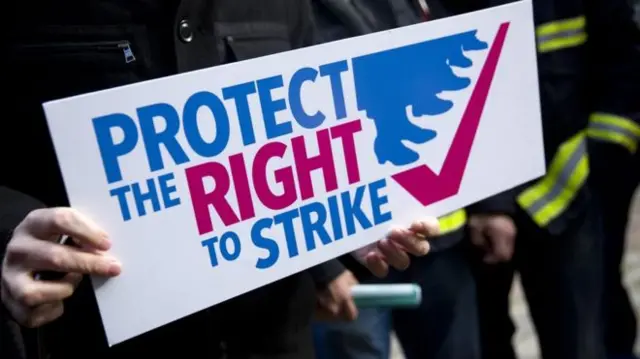 Person holding a 'protect the right to strike' sign