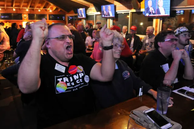 Trump supporter Ken Wilkison cheers as he watches a bar in Denver, Colorado