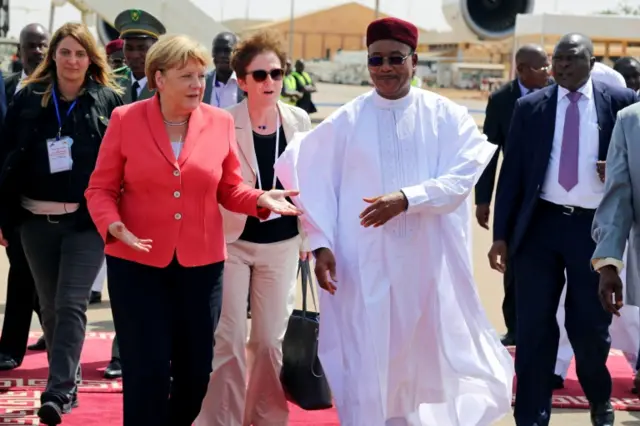 German chancellor Angela Merkel is greeted by Nigerian President Mahamadou Issoufou upon her arrival in Niamey, Niger