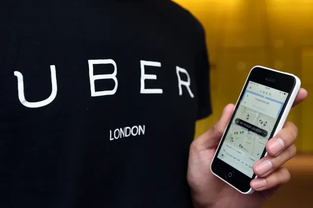 Uber logo on tee shirt with hand holding app on smartphone