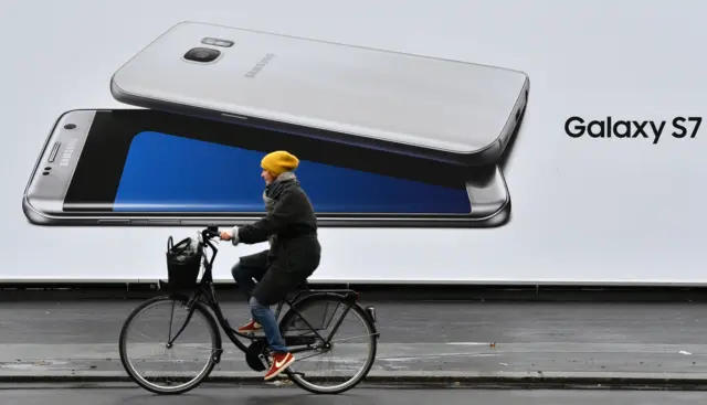 Woman cycles past Galaxy 7 sign