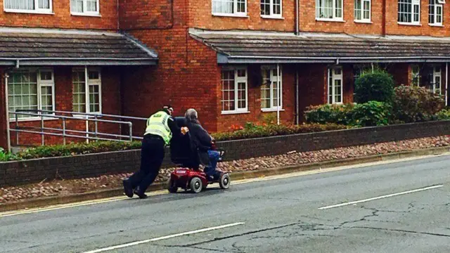 Police officer pushing scooter