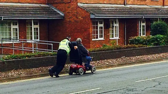 Police officer pushing scooter