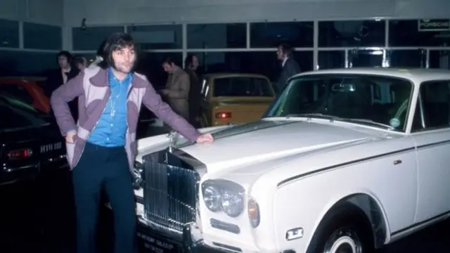 George Best standing next to the car