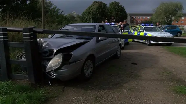 Crashed car with police cars behind