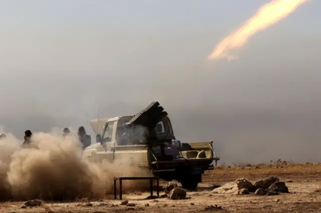 Iraqi Kurdish Peshmerga fighters fire a multiple rocket launcher from the top of Mount Zardak