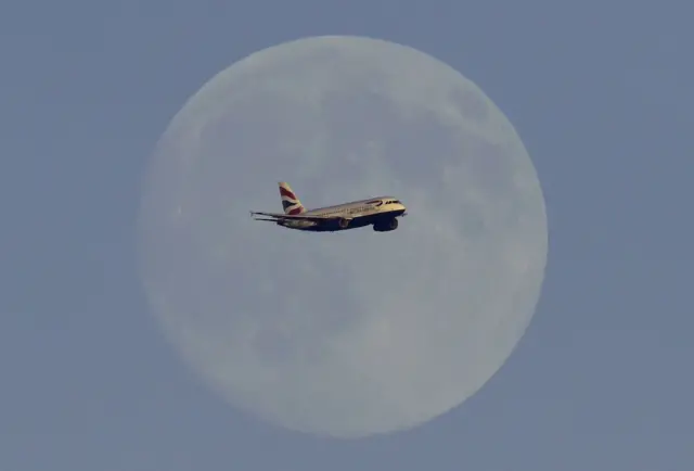 a BA plane flies in front of the moon