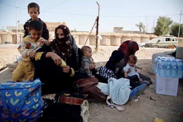 Two mothers sit with their children at the Dibis checkpoint, near the Iraqi city of Kirkuk.