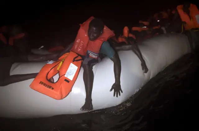 Migrants and refugees wait to be rescued from their sinking rubber boat some eight nautical miles off Libya"s Mediterranean coastline on October 12, 2016