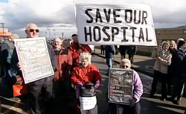 Protestors holding signs saying save our hospital