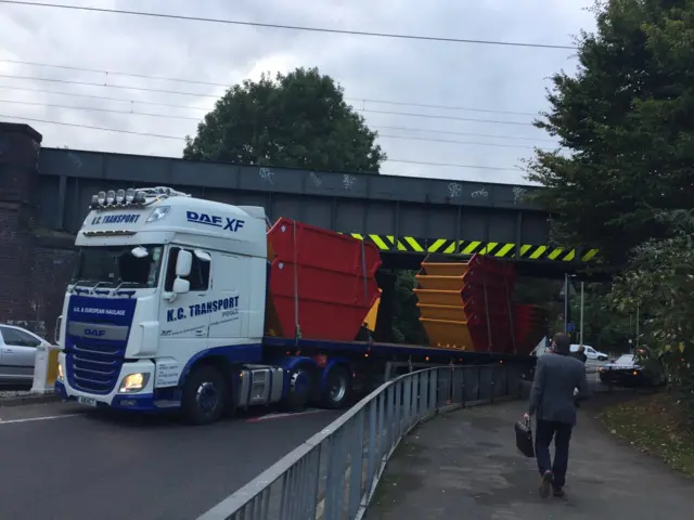 Lorry and skips under a bridge