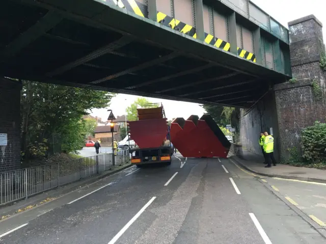 Skips and vehicle under a bridge