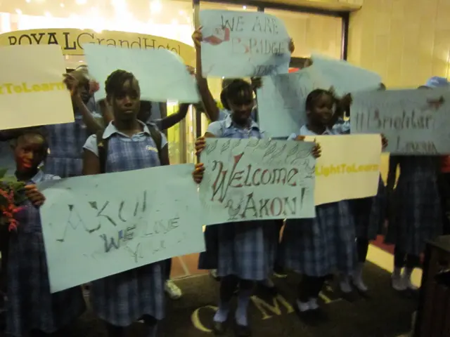 Liberian schoolchildren hold signs to welcome Akon to Monrovia