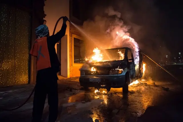 A man douses a van on fire in front of the popular jazz bar in the Braamfontein district of Johannesburg during riots involving university students protesting over planned hikes in tuition fees - October 2016