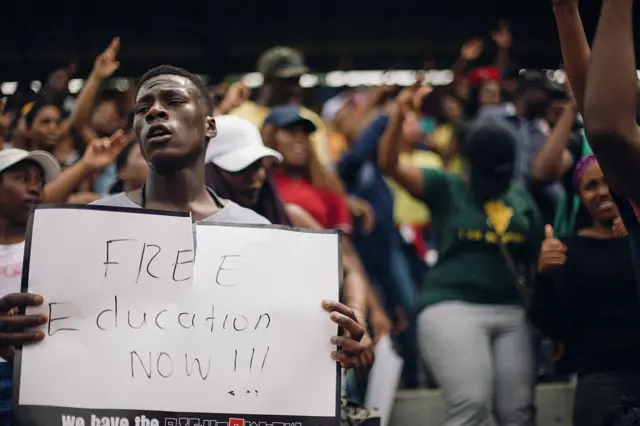 A student holding up a Free Education Now sign in South Africa