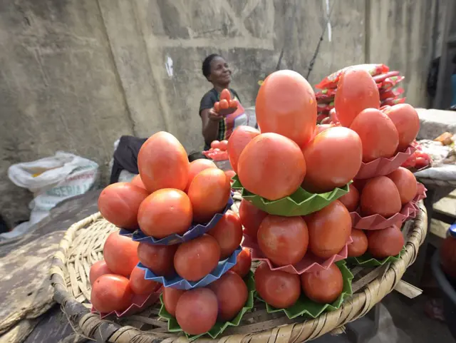 A vendor holds a tray of tomatoes for sale in the Obalende district of Lagos, on May 25, 2015