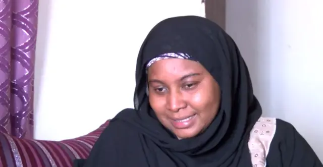 Aisha, in a hijab, weeps with joy