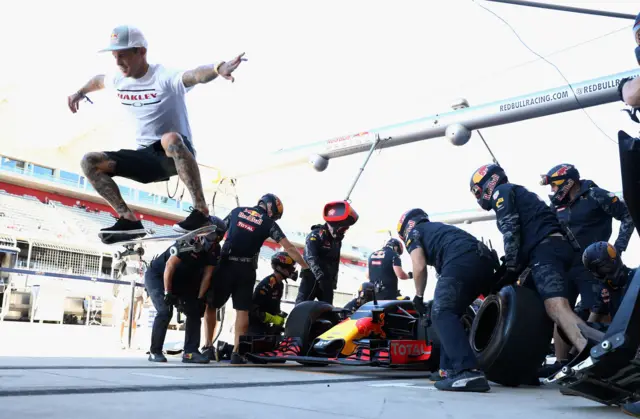 Skateboarder Ryan Sheckler performs a trick in front of the Red Bull Racing team practicing pit stop