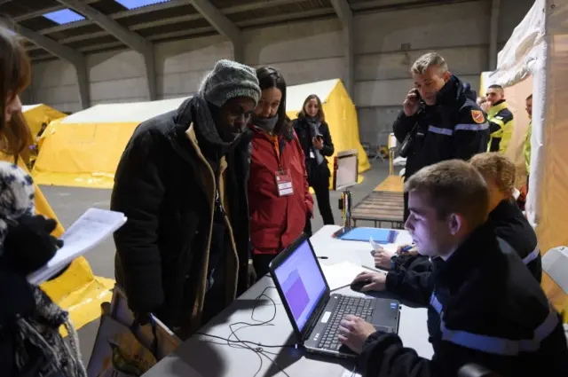 A migrant registers before boarding a bus