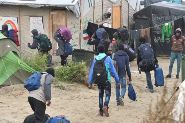 Migrants leaving the 'Jungle' camp with suitcases