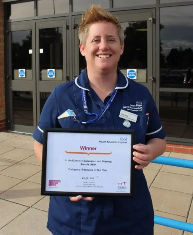 Sarah Hills, standing outside the James Paget Hospital holding her certificate