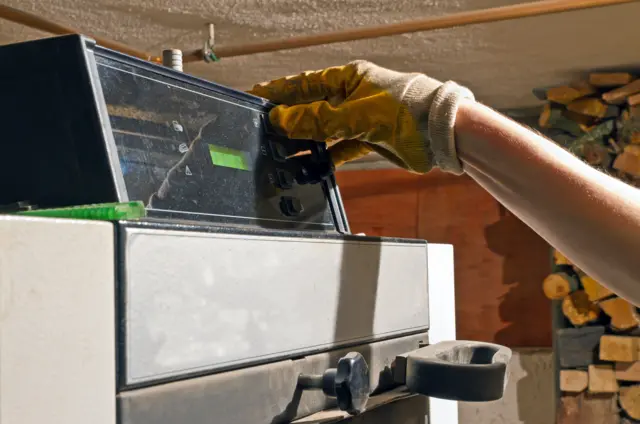 A man operates a wood boiler