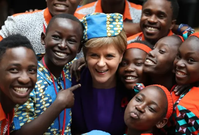 Scotland"s First Minister Nicola Sturgeon trys on a headpiece with the "Singing Children of Africa" from Kenya after they sang at the Scottish Parliament in Edinburgh during a visit to Scotland.