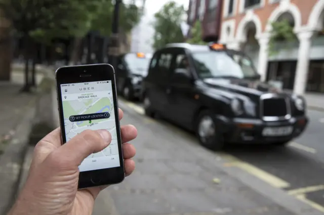 Person accessing Uber on a smartphone with a taxi in the background