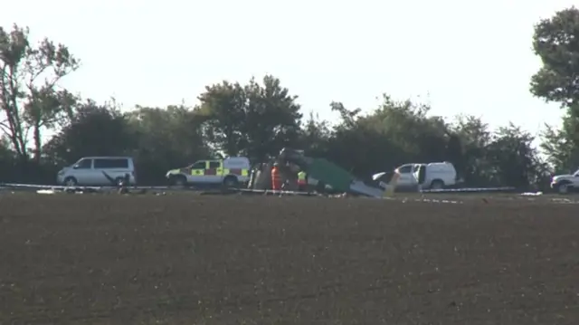 Today's scene of aircraft crash, showing vehicles and men in fluorescent outfits