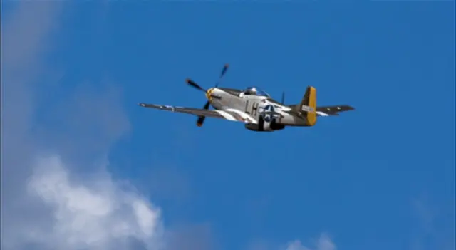 Mustang in flight, with blue skies and whispers of cloud at Old Buckenham