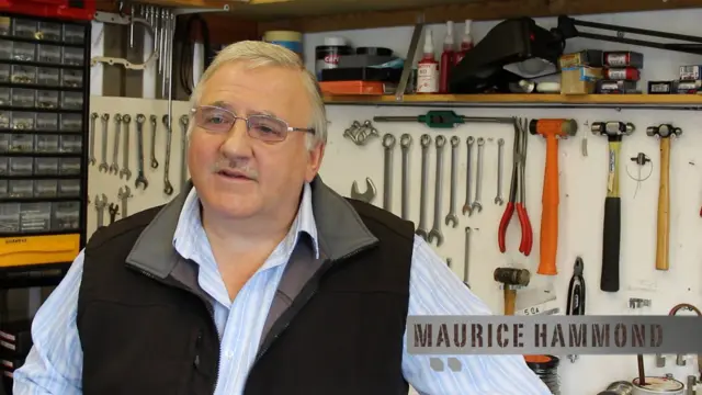 Maurice Hammond, in blue shirt, sleeveless jacket, in a workshop