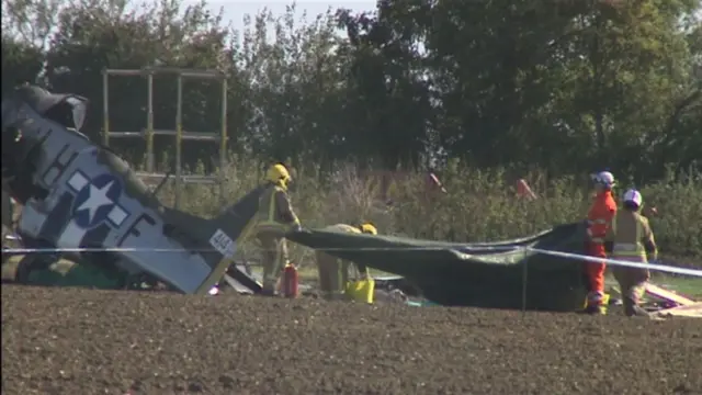 The wrecked aircraft, with investigators removing wreckage