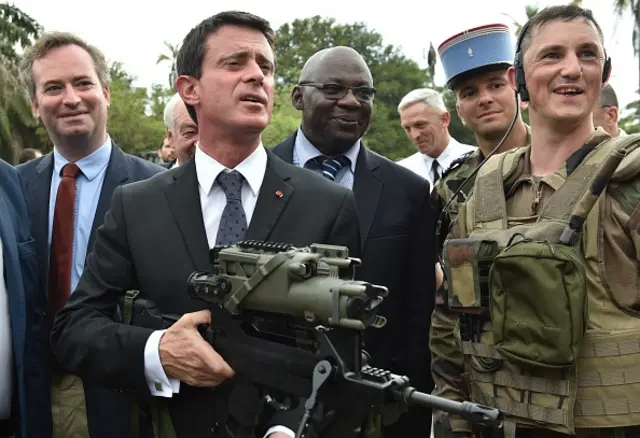 French Prime minister Manuel Valls holds a FAMAS assault rifle as he visits the 43e BIMA French military compound in Abidjan on October 30, 2016, during the last leg of his West African tour.