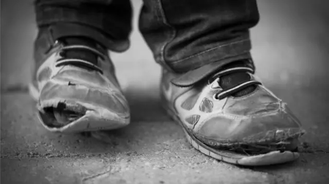 Child wearing ripped trainers