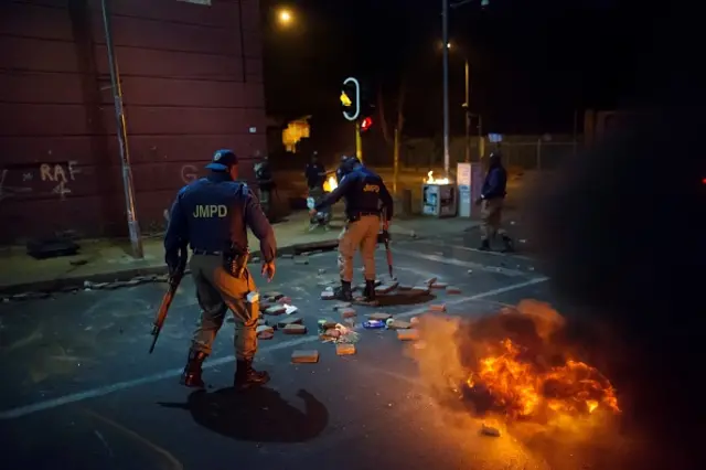 South African police officers dismantle a barricade in the Doornfontein district of Johannesburg after students of the local University of Johannesburg campus clashed with private security guards on September 28, 2016