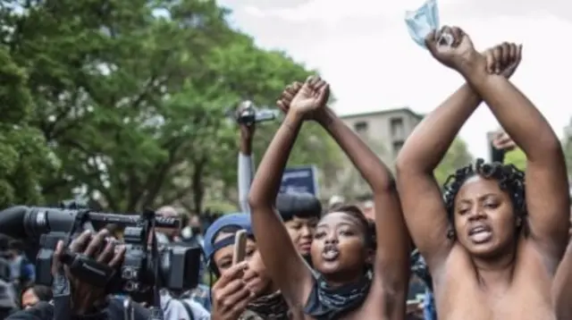 Bare chest students gesture at the University of Witwatersrand in Johannesburg on October 4, 2016 in an act of defiance against South African anti riot policemen during a mass demonstration.