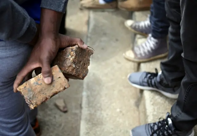 A student holds rocks during clashes with the South African police at Johannesburg"s University of the Witwatersrand, South Africa, October 4,2016