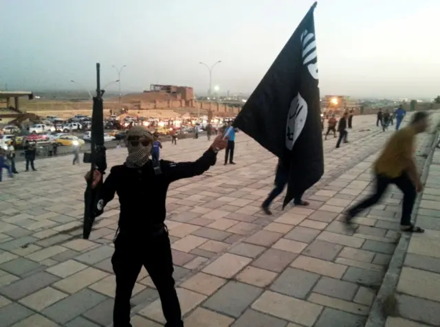 A gunman holds a so-called Islamic State flag in Mosul, Iraq