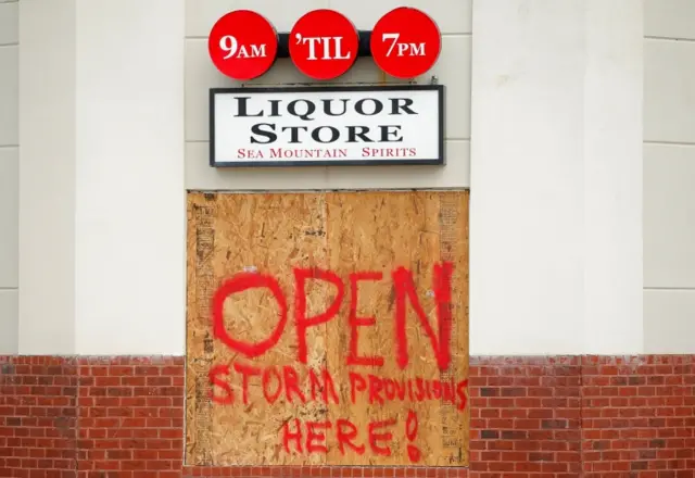 A message is written on a plywood board covering a window at a local liquor store ahead of Hurricane Matthew in Cherry Grove