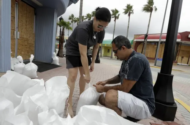 Miroslava Roznovjakova and Ray Hayyat place sandbags in front of their store to guard against flooding in Daytona Beach, Florida