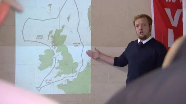 Alan Brown standing by a wall map, showing the 200 mile limit around UK