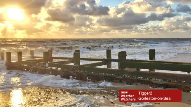Sunshine through clouds, with crashing waves, at Gorleston beach