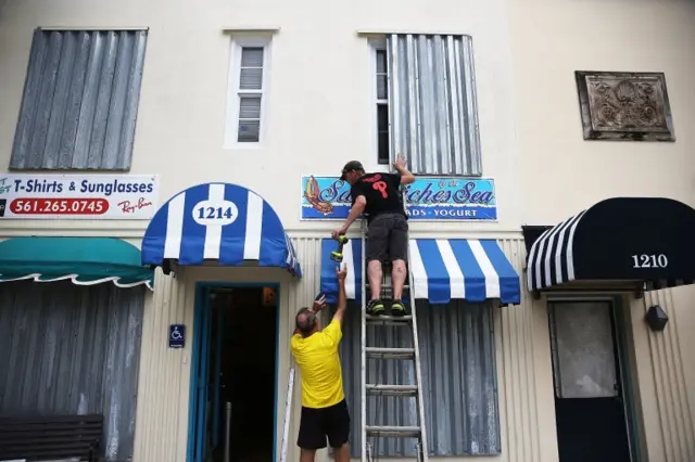 Danny Askins and Brenden Kavana put up hurricane shutters at a restaurant