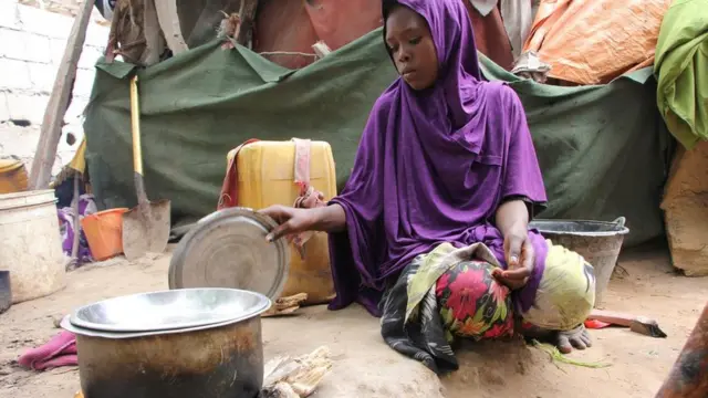 Somali young girl cooks food outside their makeshift home inside a refugee camp in Mogadishu, Somalia, Tuesday, Sept. 20, 2016.