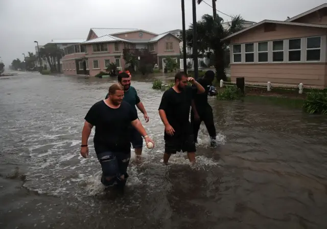 Local residents wade through a flooded street in Jacksonville