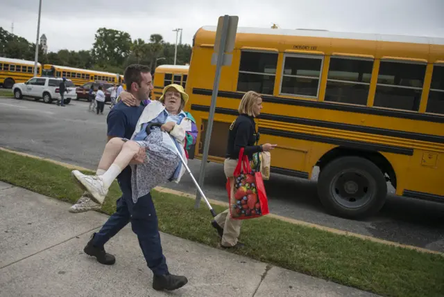 Firefighter carries woman to bus at Civic Center, Savannah, during evacuation ahead of Hurricane Matthew, Thursday, Oct 6, 2016