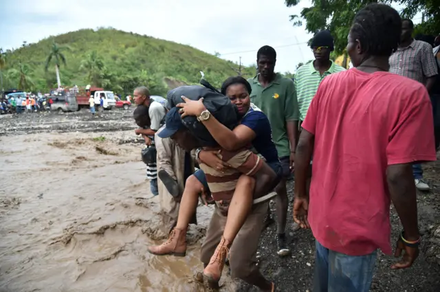 Haitian people cross the river La Digue in Petit Goave where the bridge collapsed during the rains from Hurricane Matthew, south-west of Port-au-Prince