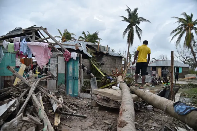 A young man walks on the trunk of a palm tree in front of a destroyed house after Hurricane Matthew, in Croix Marche-a-Terre, in South-west Haiti, on 6 October, 2016